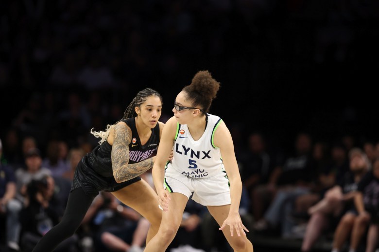 Golden State Valkyries wing Gabby Williams guards Minnesota Lynx guard Olivia Miles. They are both shown from the front with an out of focus crowd behind them.