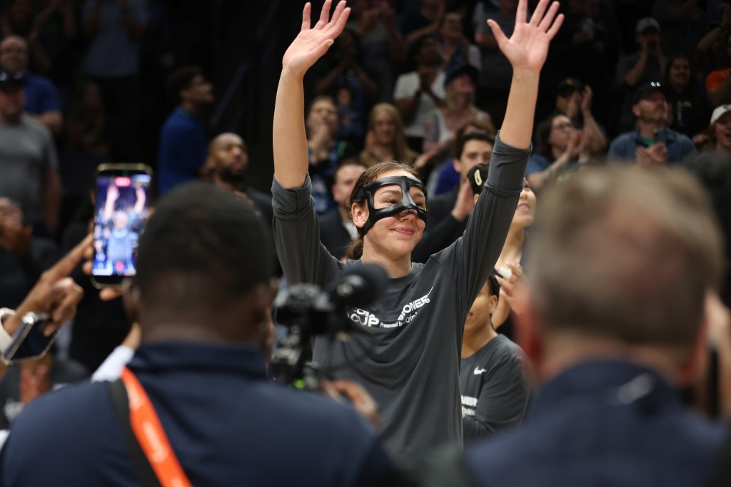 Alanna Smith with a mask on her face raises both of her arms to acknowledge Lynx fans in Minneapolis