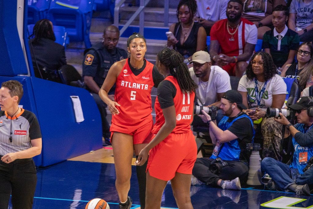 Angel Reese and Madina Okot, both in red jerseys, talk during a game when the Atlanta Dream played the Dallas Wings in Dallas.