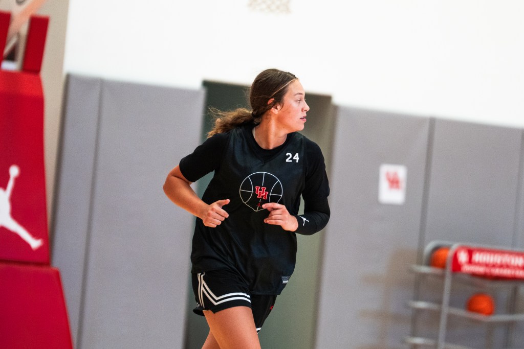 A player in a black Houston practice uniform runs on the court during a drill. 