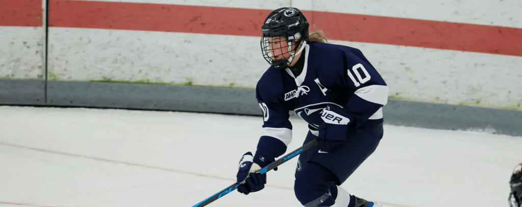 Stecker looks up ice as she starts a breakout. She is wearing a navy Penn State uniform.