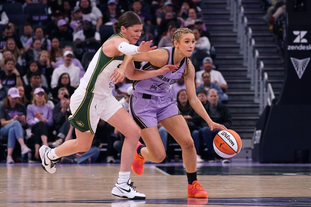 Golden State Valkyries guard Miela Sowah dribbles with her left hand and scans the court. A Seattle Storm defender is draped on her right side.