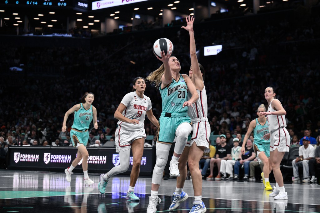Sabrina Ionescu lays the ball up to the basket with a Mystics defender contesting her