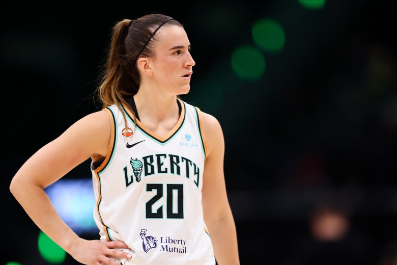 Sabrina Ionescu stares with right hand on her right hip.