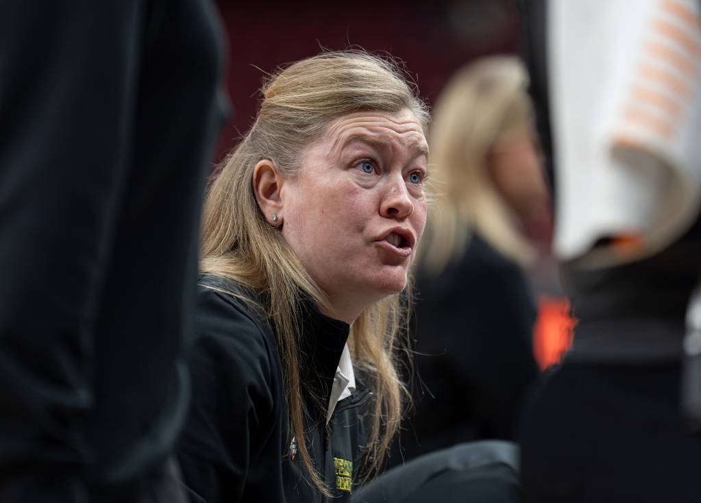 With her eyebrows raised, Vermont head coach Alisa Kresge talks to her team in a huddle during a timeout. It's a close-up view of her, from about the shoulders up.