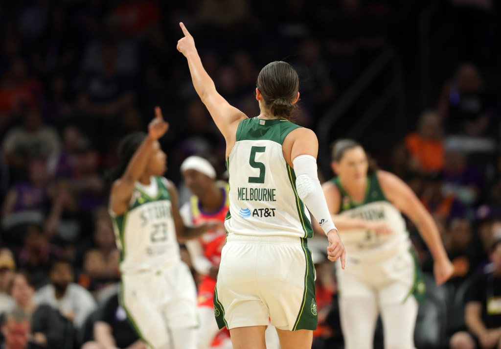 Seattle Storm guard Jade Melbourne is shown from behind, pointing to a teammate in the background with her left hand.