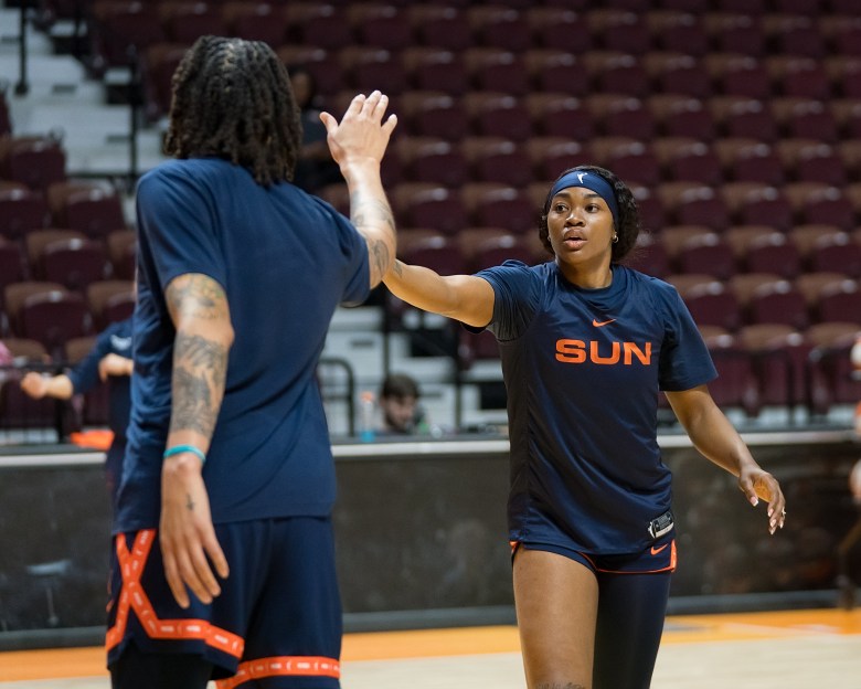 Brittney Grinet with back to camera high five's Aneesah Morrow.