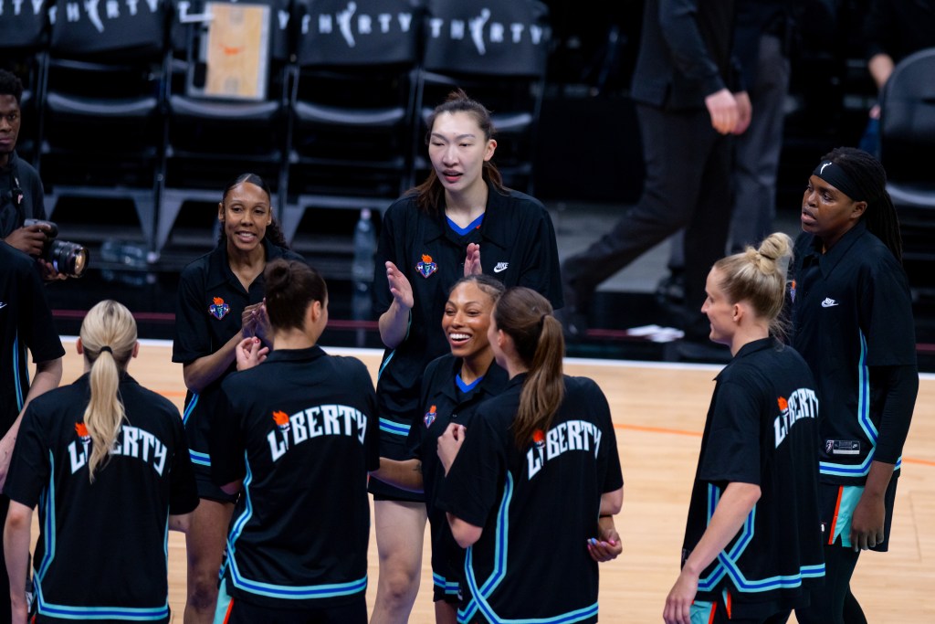 Betnijah Laney-Hamilton smiles wide while huddling with her teammates.