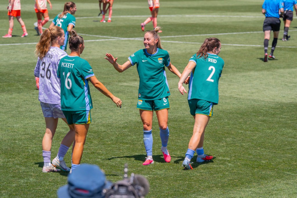 Denver Summit FC defender Janine Sonis (6) smiles and holds her hand up for a high-five with three of her teammates following their win against the Portland Thorns.