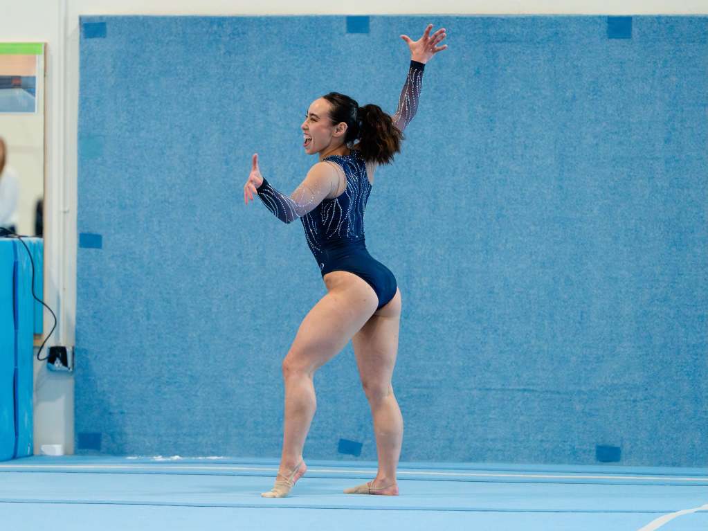 Gymnast Katelyn Ohashi performs in a blue leotard in front of a blue background
