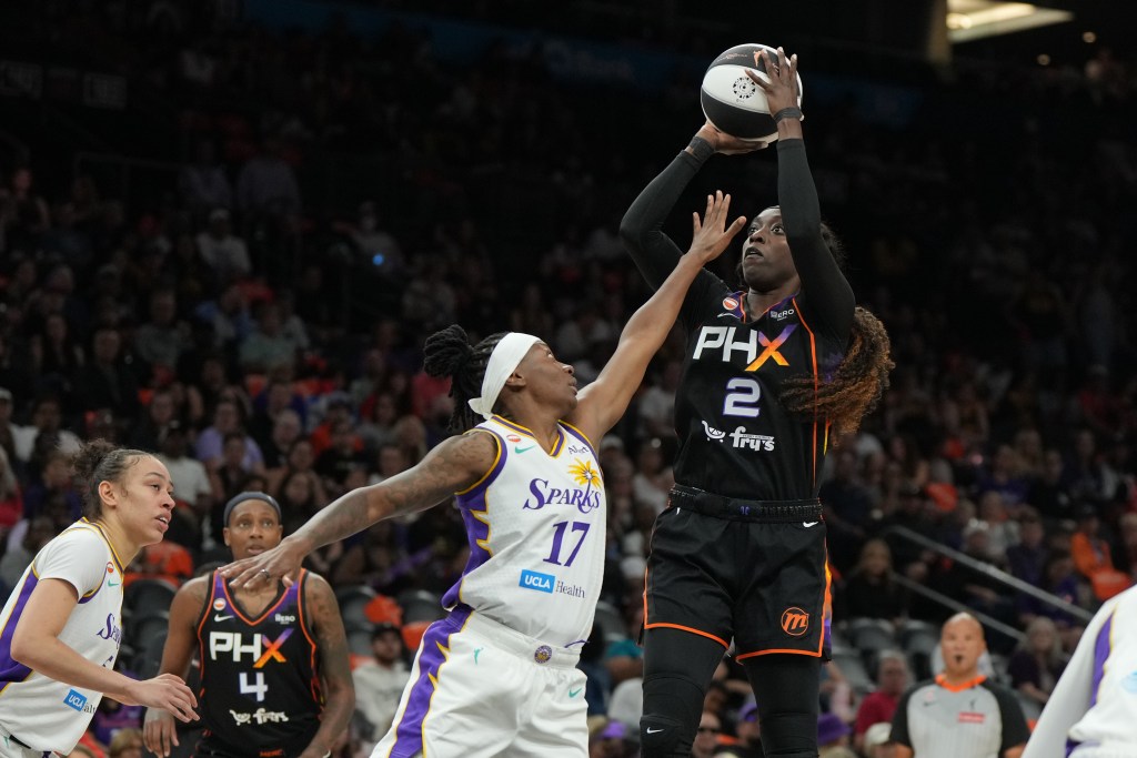 Kahleah Copper in a black "PHX" uniform attempts a jump shot while a Los Angeles Sparks player in a white uniform defends.