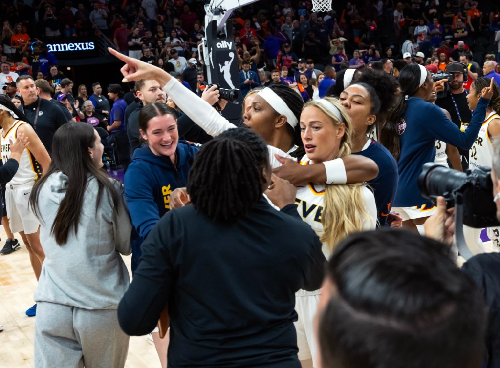 Fever players and staff celebrate energetically on the court, as Sophie Cunningham points, creating a joyful and victorious atmosphere.