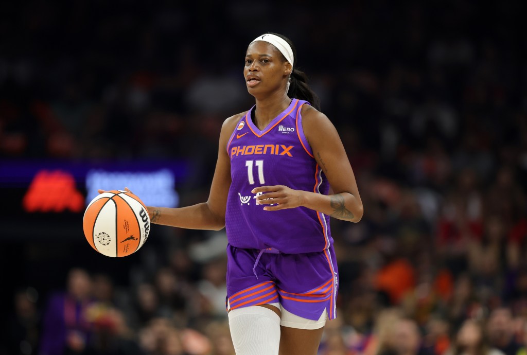 Valeriane Ayayi dribbles the basketball up the court during a game, wearing a purple Phoenix uniform with a white headband.