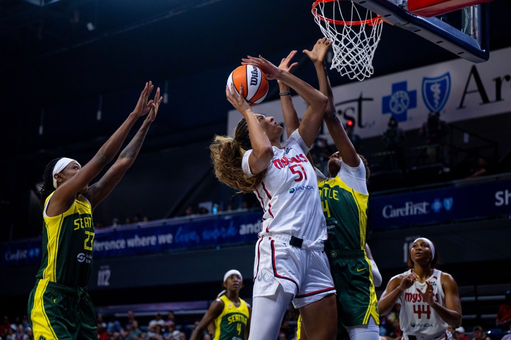 Washington Mystics center Lauren Betts tries to shoot a layup from close range with a defender pressed against her.
