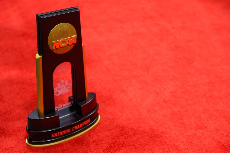 An NCAA ice hockey championship trophy sits on a red carpet.