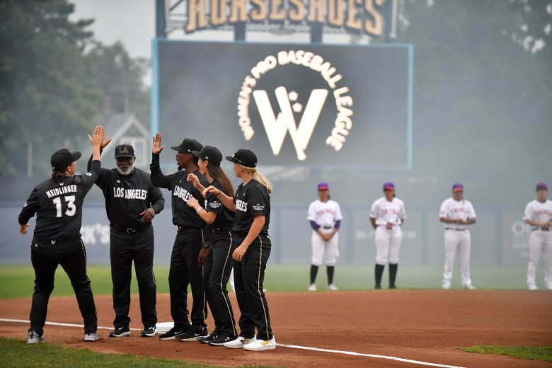 The Los Angeles Queens huddle with the opposing New York Heights behind them. In the background is a large screen with the WPBL logo.