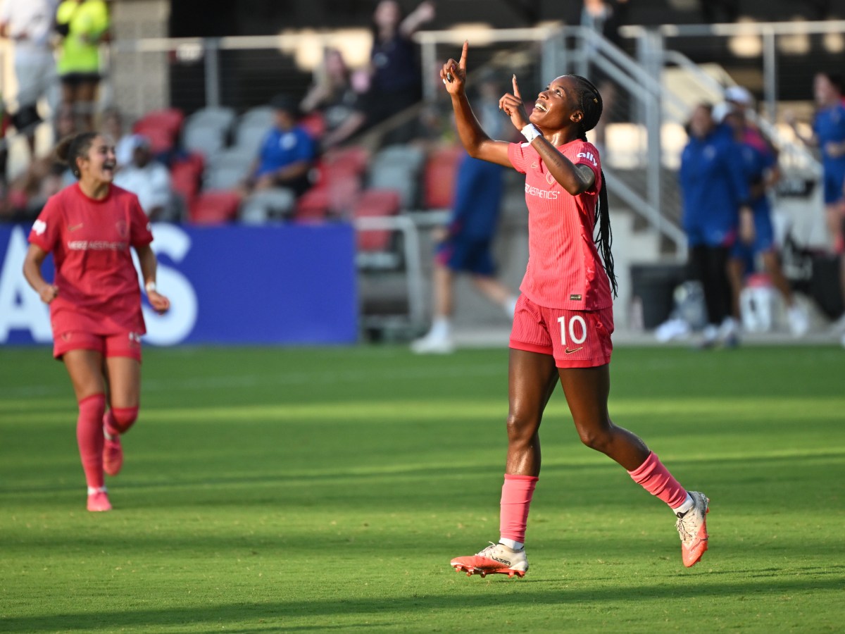 Evelyn Ijeh smiles and lifts both pointer fingers to the sky, celebrating a goal.