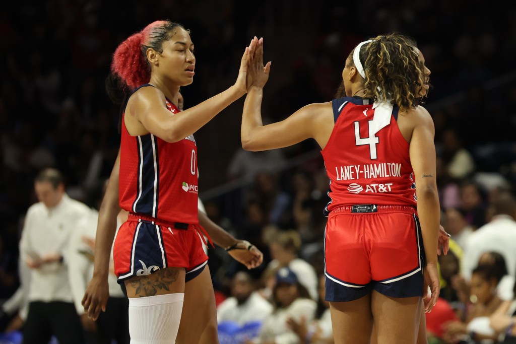 Washington Mystics center Shakira Austin and guard/forward Betnijah Laney-Hamilton high-five. Austin is shown from the side, reaching her right arm out for the high-five. Laney-Hamilton is shown from behind, extending her left arm.