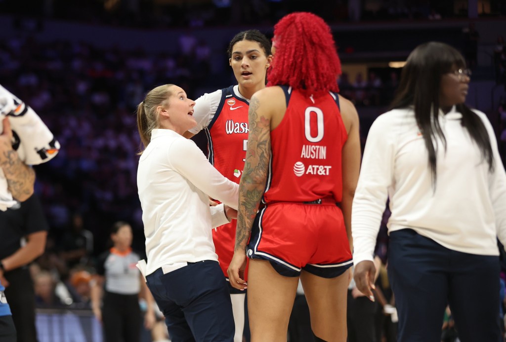 Washington Mystics assistant coach Jessie Miller stands in a small huddle with centers Shakira Austin and Lauren Betts and gives them instructions.