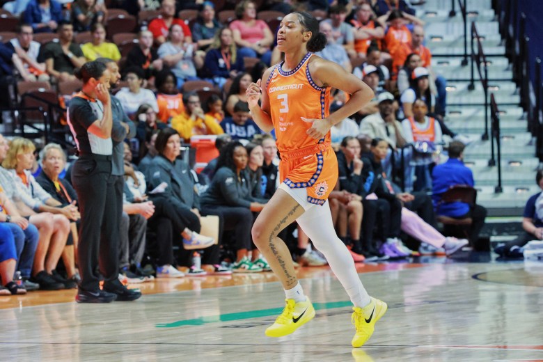 Ashlom Jackson, wearing an orange No. 3 jersey is running and is wearing a white leg sleeve on her right leg.