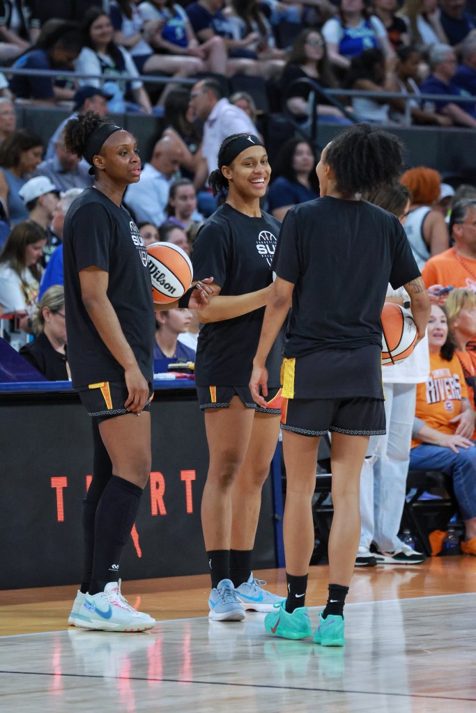 Connecticut Sun players Kennedy Burke, Leïla Lacan and Nell Angloma stand together wearing black shirts and shorts exchanging laughs before their game.