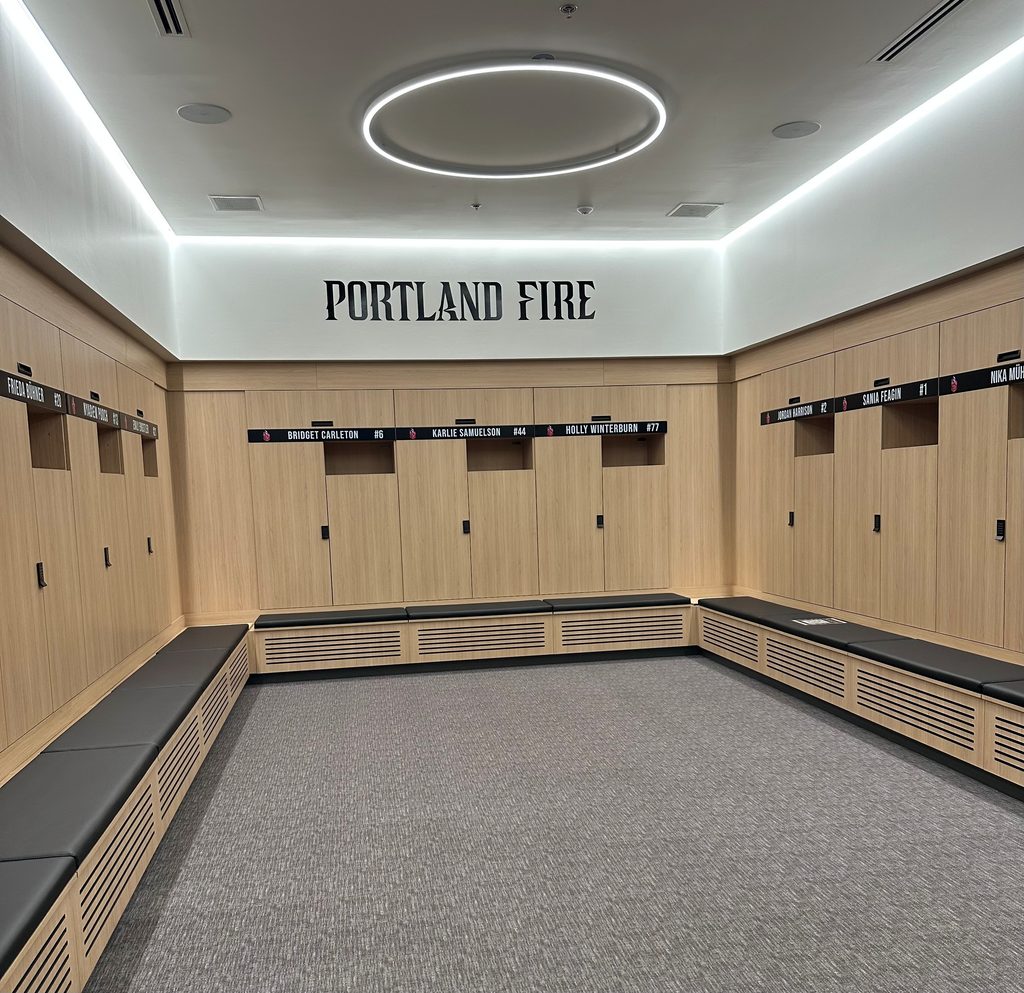 A photo of the Portland Fire locker room, with wood paneling and doors along 3 walls accented by black player nameplates