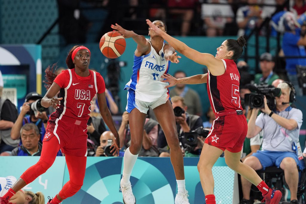 France's Valeriane Ayayi leaps to passthe ball between USA's Kahleah Copper wearing No. 7 and Kelsey Plum wearing No. 5.
