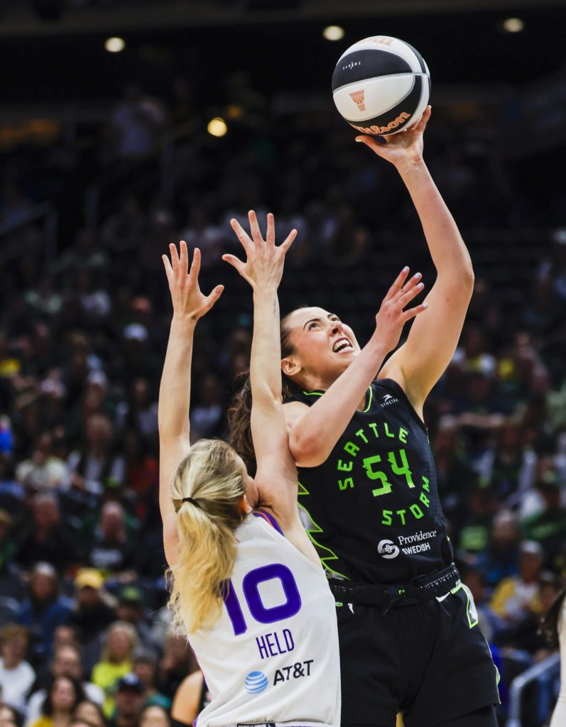 Mackenzie Holmes grimaces as she lifts the ball towards the basket with one hand, <a rel=