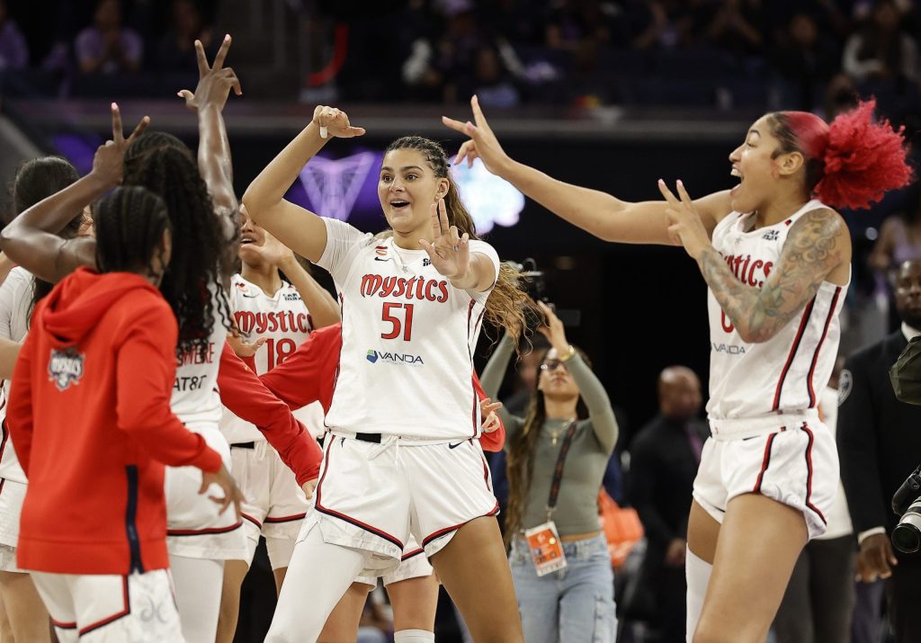 Washington Mystics players dance to celebrate a win over the Golden State Valkyries. They are holding up three fingers on each hand, recreating a meme that teammate Sonia Citron inadvertently started during her rookie season.