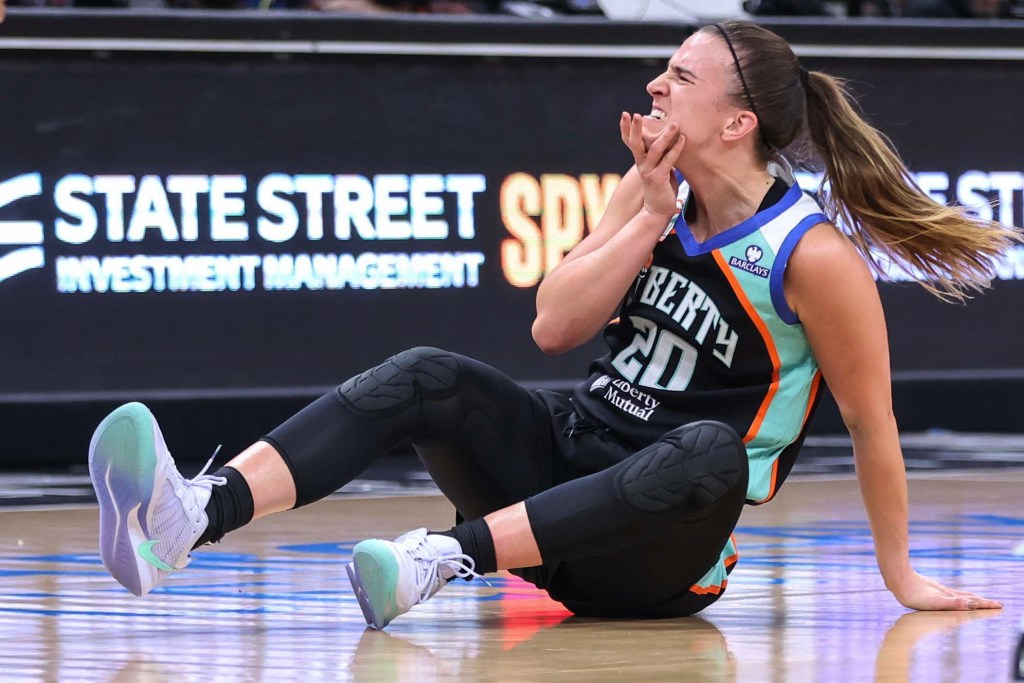 Sabrina Ionescu holds her chin after falling to the ground and taking a charge