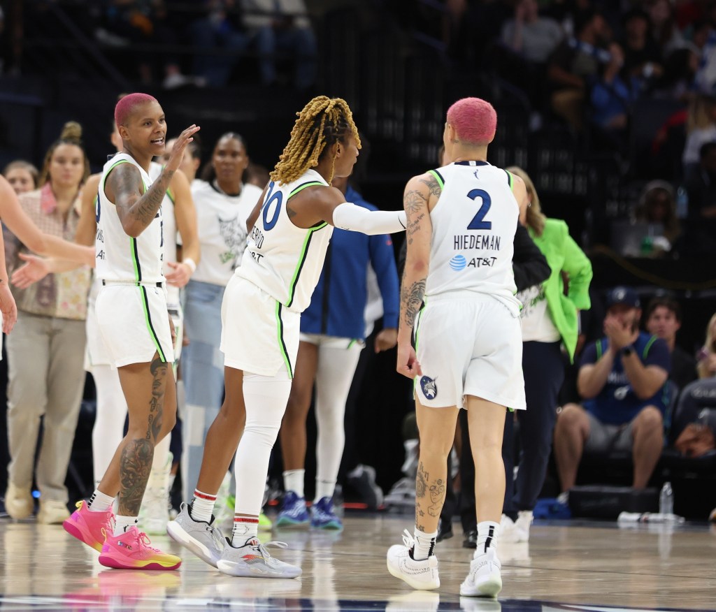 A group of players in white jerseys high-five and support each other on the basketball court