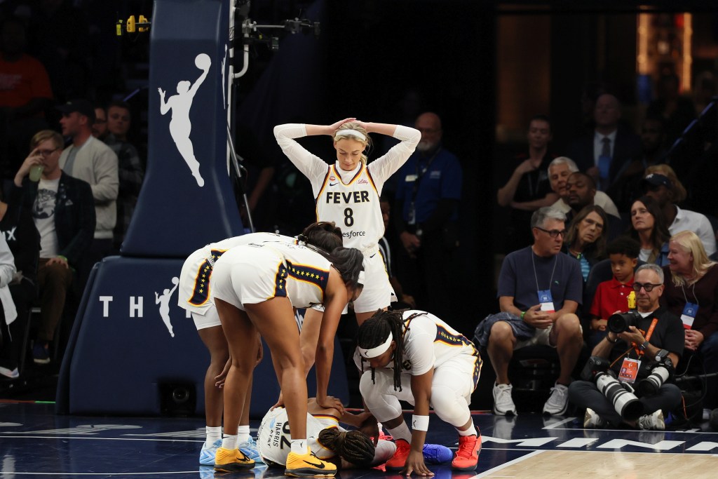 Injured Indiana Fever guard Ty Harris lays on the court while surrounded by Fever teammates.