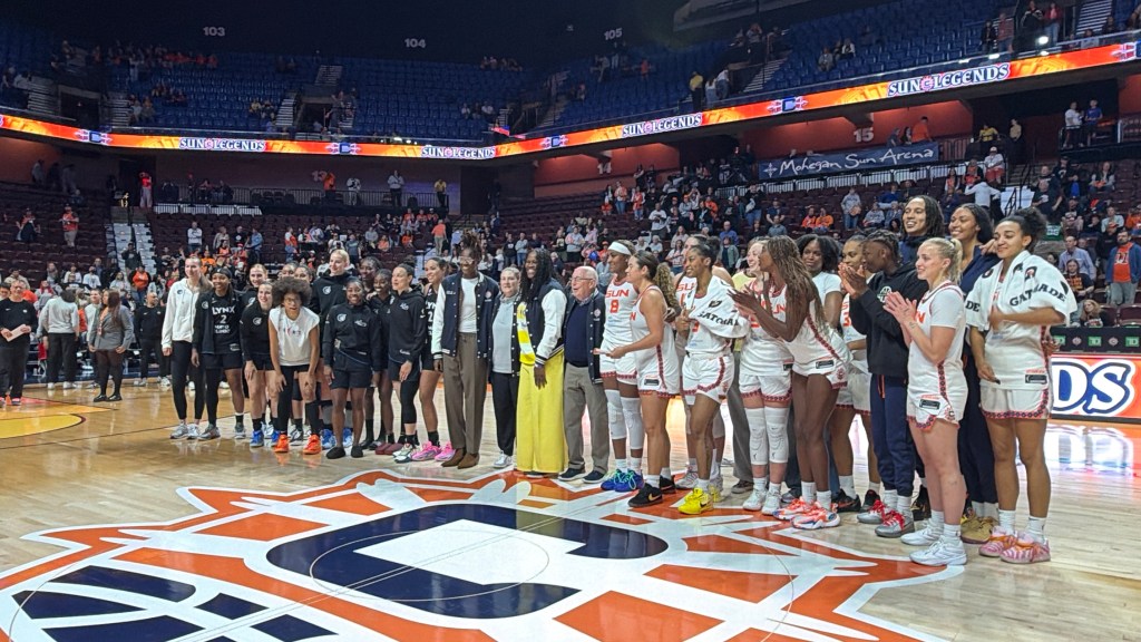 Members of the Connecticut Sun and the Minnesota Lynx smile together for a photo at center court to honor Sun legend and former head coach, Mike Thibault.