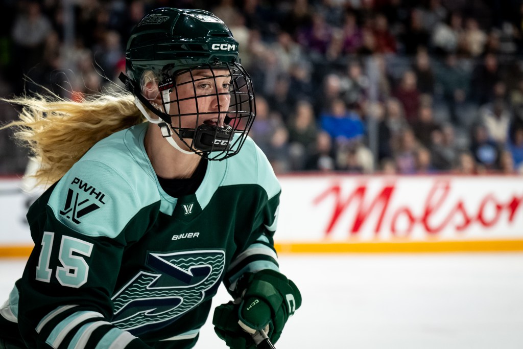 A waist-up shot of Mobley as she looks to her right while skating. She is wearing a green home uniform.
