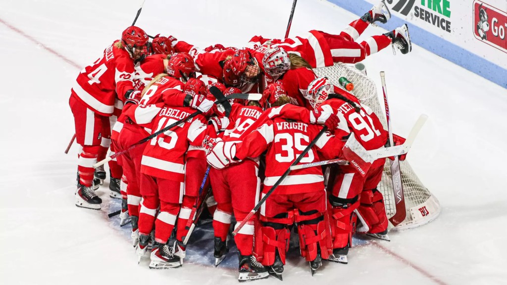 A hockey team huddles around their net.