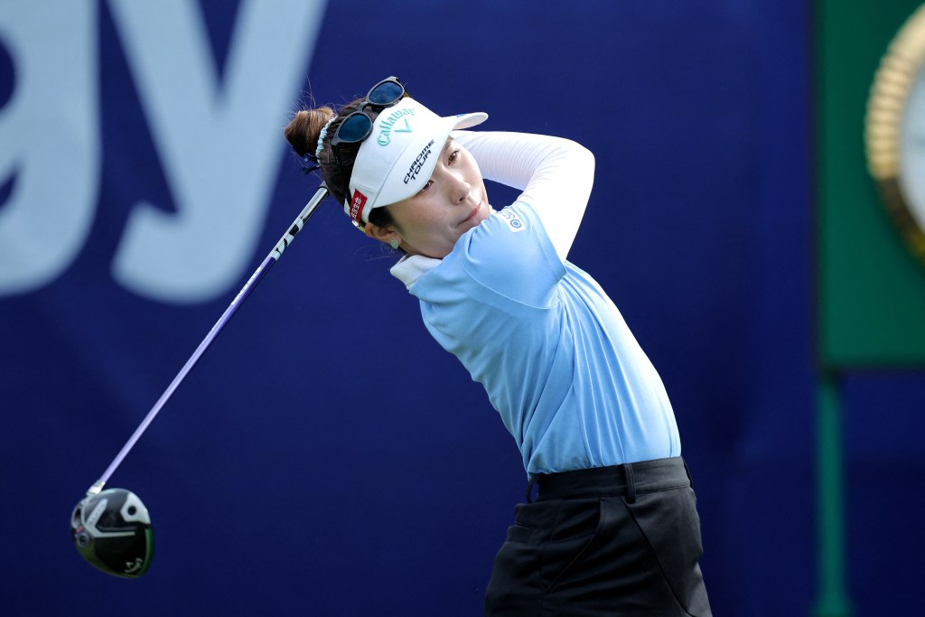 Yuna Nishimura hits a golf shot, her hands and the club in the follow-through position behind her head
