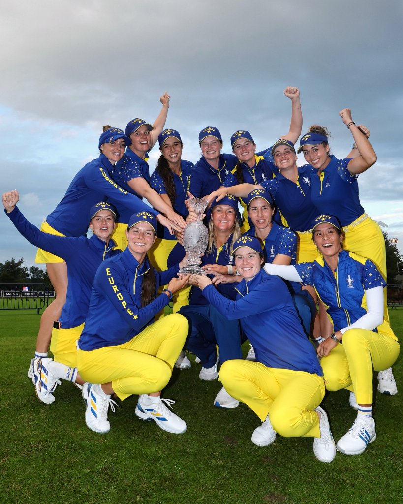 Members of Team Europe gather around Captain Anna Nordqvist, who kneels and holds the Solheim Cup in her hands, for a group photo