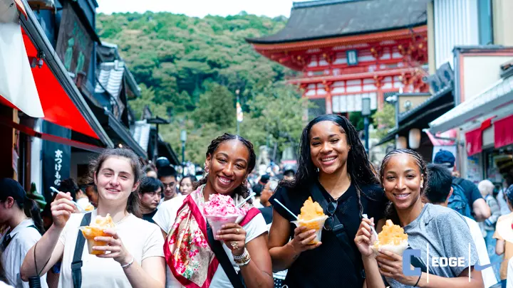 Four Columbia players hold icy treats and smile for the camera. Behind them, a historic temple is visible.
