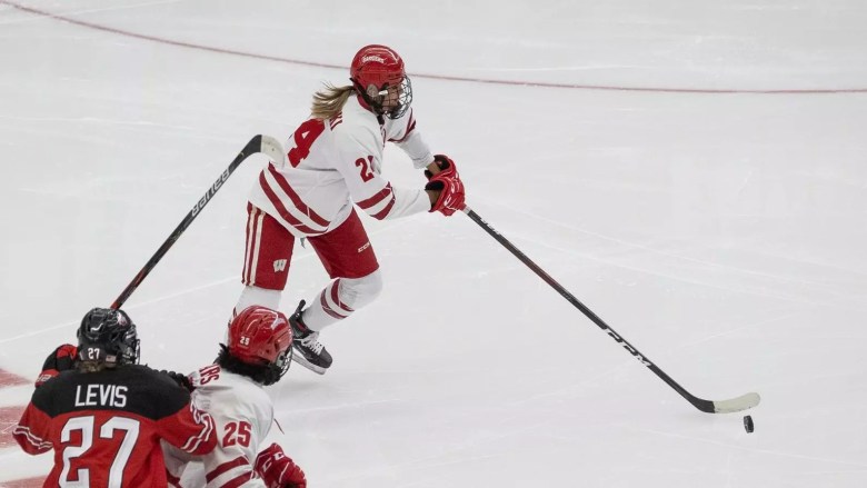 A women's ice hockey player skates with the puck.
