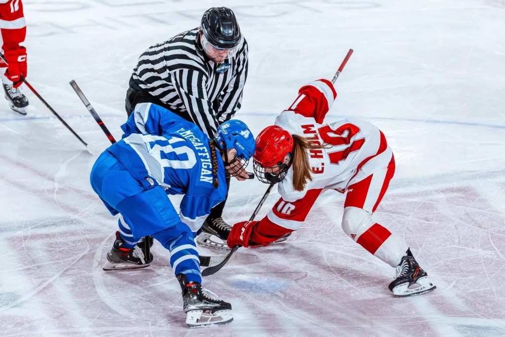 Two women’s hockey players line up for a face-off.