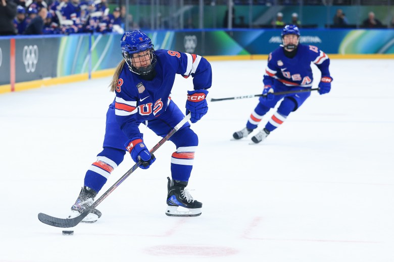 Winn looks toward the middle of the ice as she carries the puck. She is wearing a blue home USA uniform.