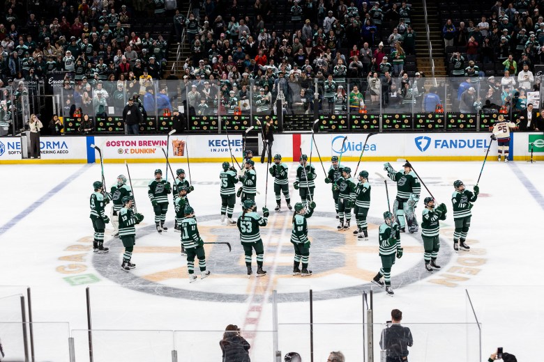 The Fleet stand around the center ice circle and salute the crowd following their TD Garden debut. They are wearing green home uniforms.