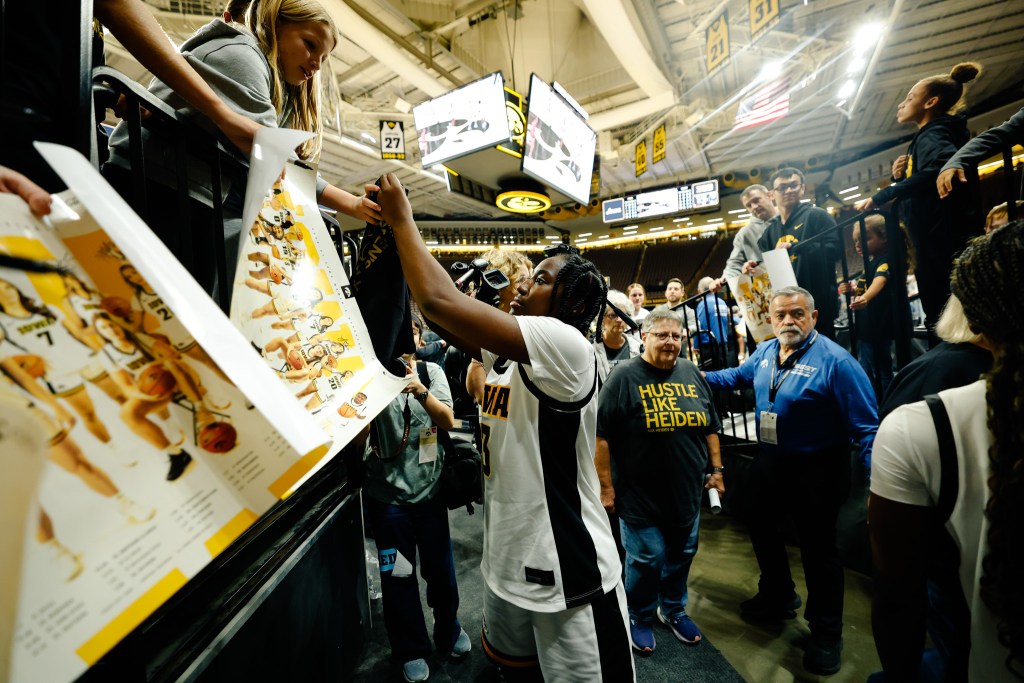 Young fans hold their Iowa posters out for guard Dani Carnegie to sign autographs after an exhibition game at Carver-Hawkeye Arena.
