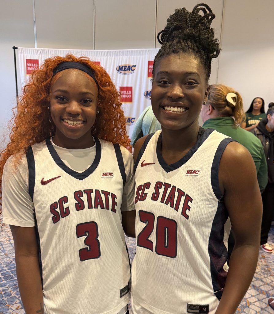 Two players in white uniforms smile.