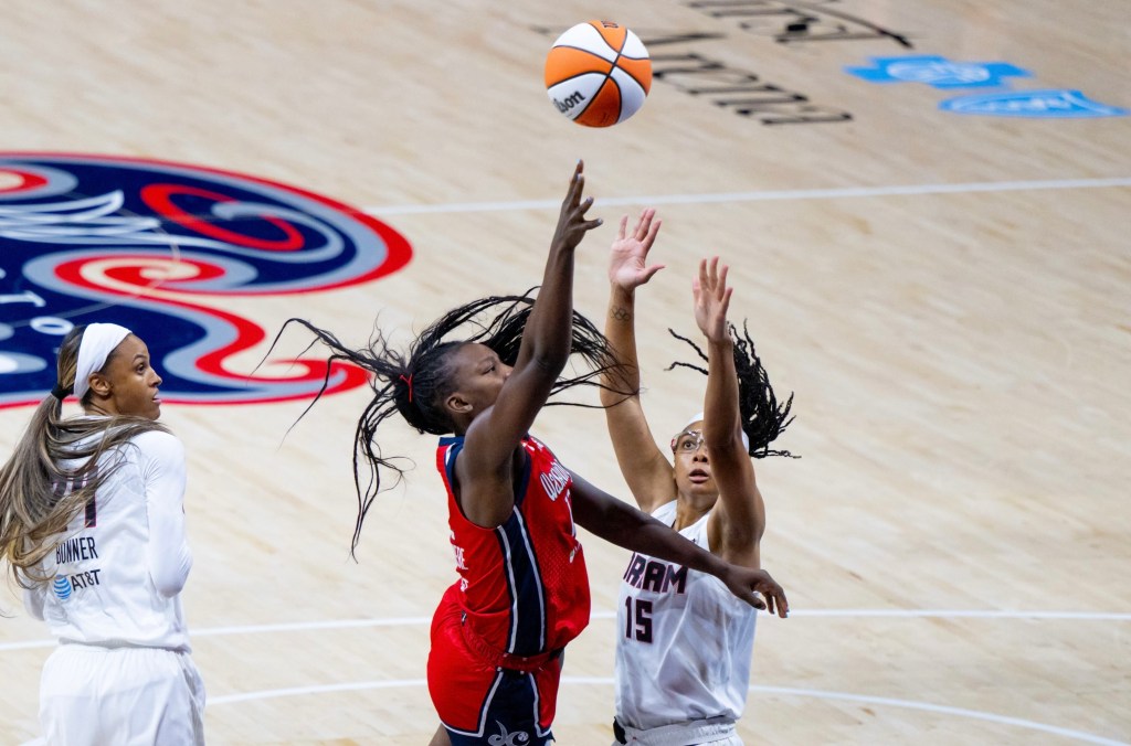 Washington Mystics forward Michaela Onyenwere shoots a right-handed floater over Atlanta Dream guard Allisha Gray. Gray's eyes are locked in on the ball, and her arms are straight up to contest the shot.