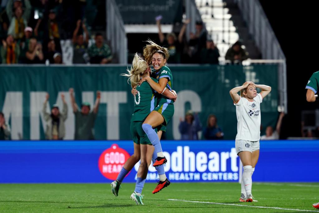 Janine Sonis has jumped into the arms of Lindsey Heaps and is held at hip height as she screams in celebrations.