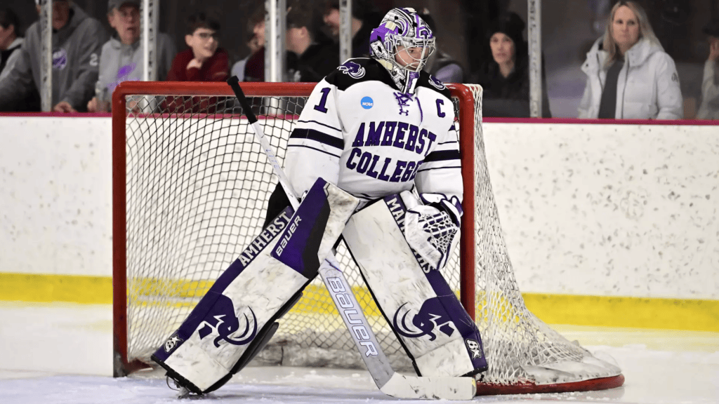 Stott looks to her left as she tracks the puck. She is wearing a white uniform.